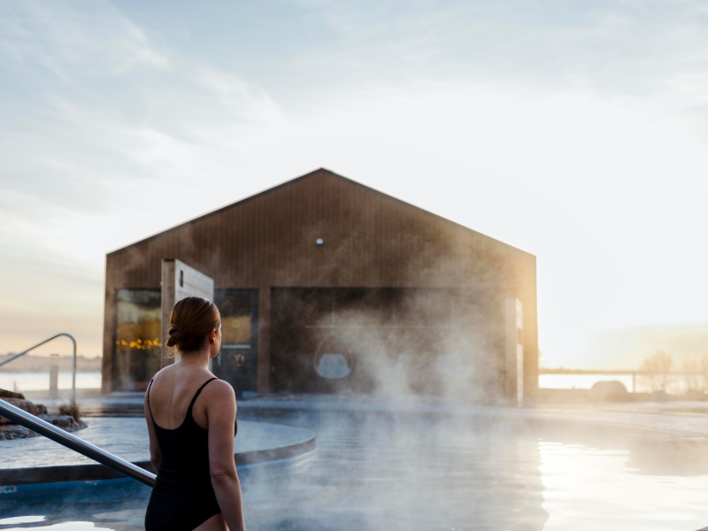 Person stands in hot tub looking over St. Peter's Bay in winter