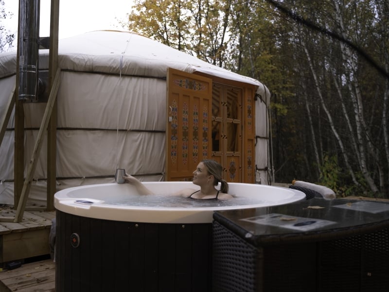 Female sitting in a hot tub outside of a Mongolian Yurt