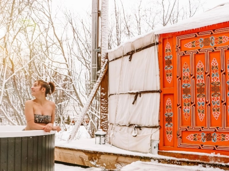 Woman in hot tub outside yurt in winter