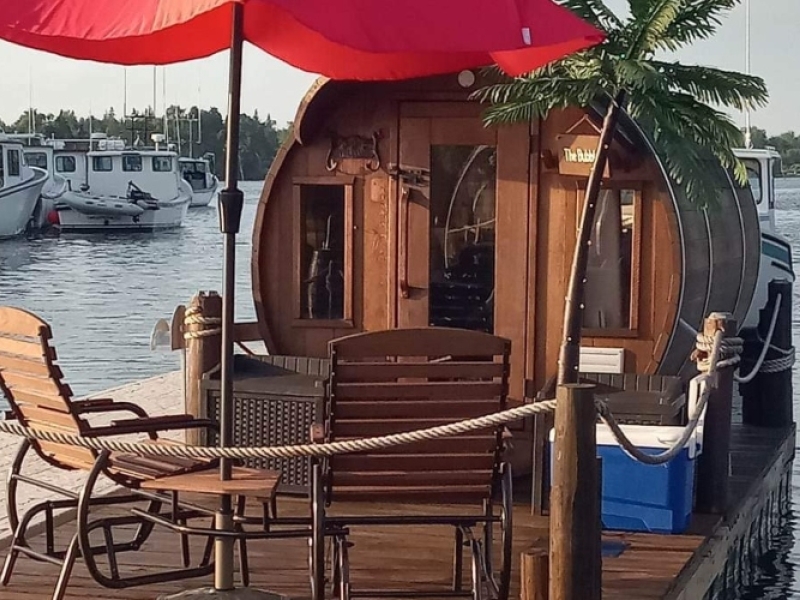 Wine barrel accommodations on a floating dock with deck and outdoor lawn chairs and umbrella