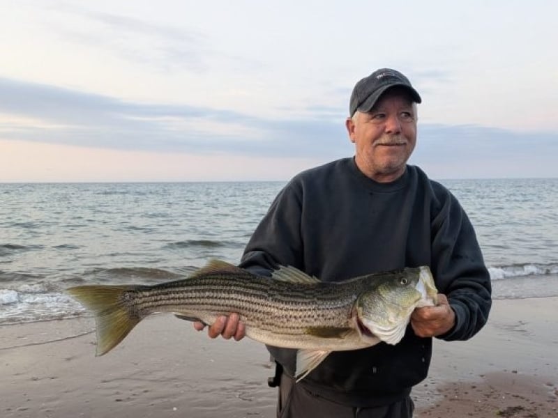 Man holds large bass next to north shore