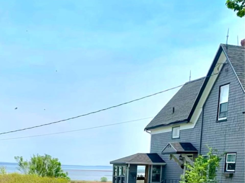 outside photo looking at a large grey home beside water
