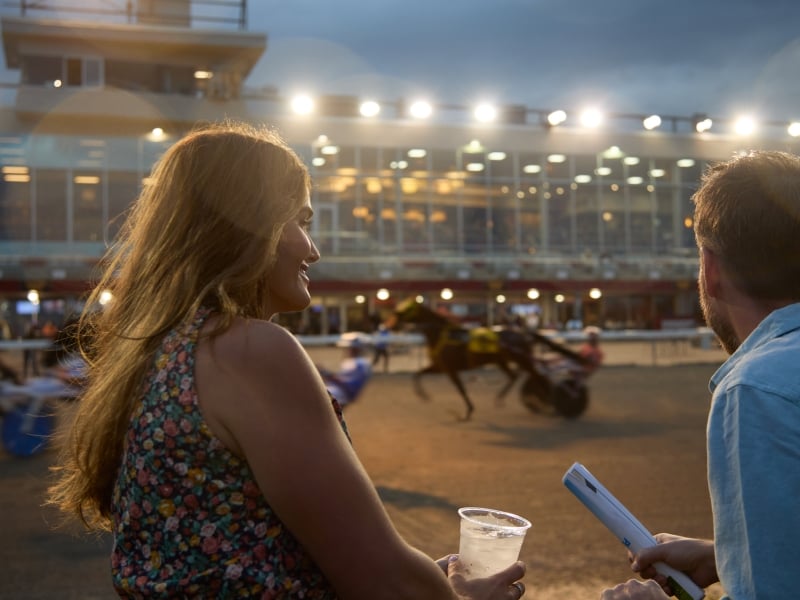 Couple looking over fence and watching horse race