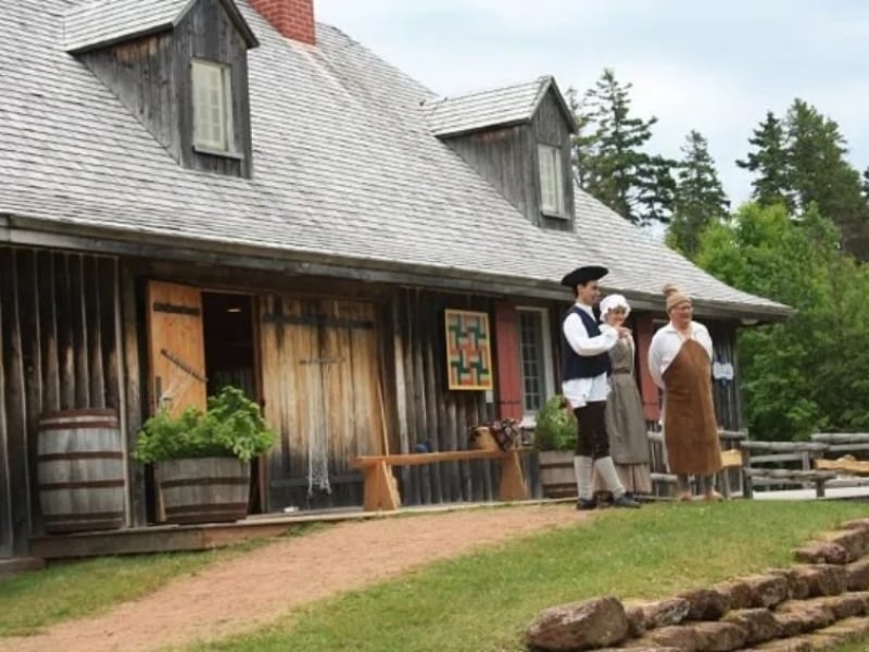 outside view looking at wood structure of main building tree people dressed in period costumes standing in front