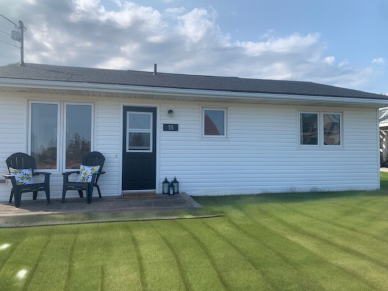 outside view of a white cottage with deck and two chairs