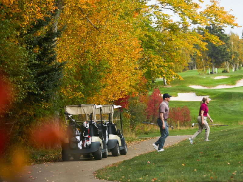 Image of couple with golf cart at Green Gables Golf Course in fall