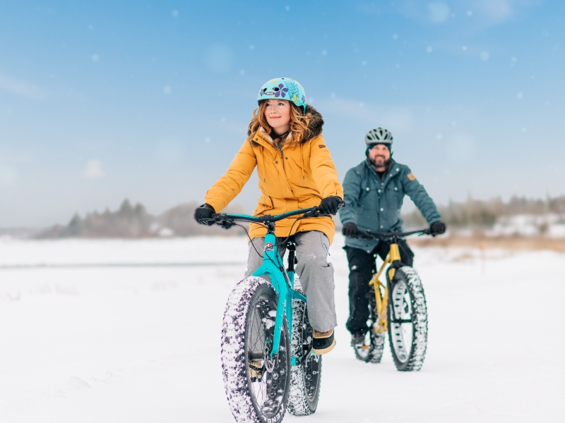 Couple on fat bikes across snowy field
