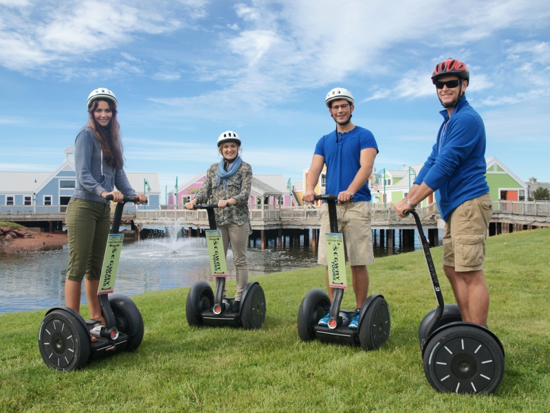 Four adults wearing helmets riding out for a ride on Segways