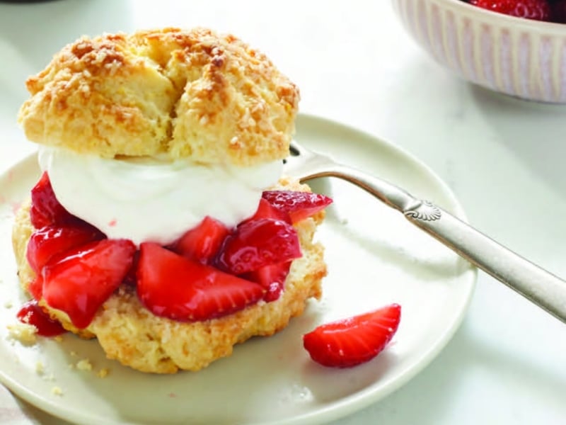 Strawberry shortcake on a plate with fork with bowl of fresh strawberries to the side