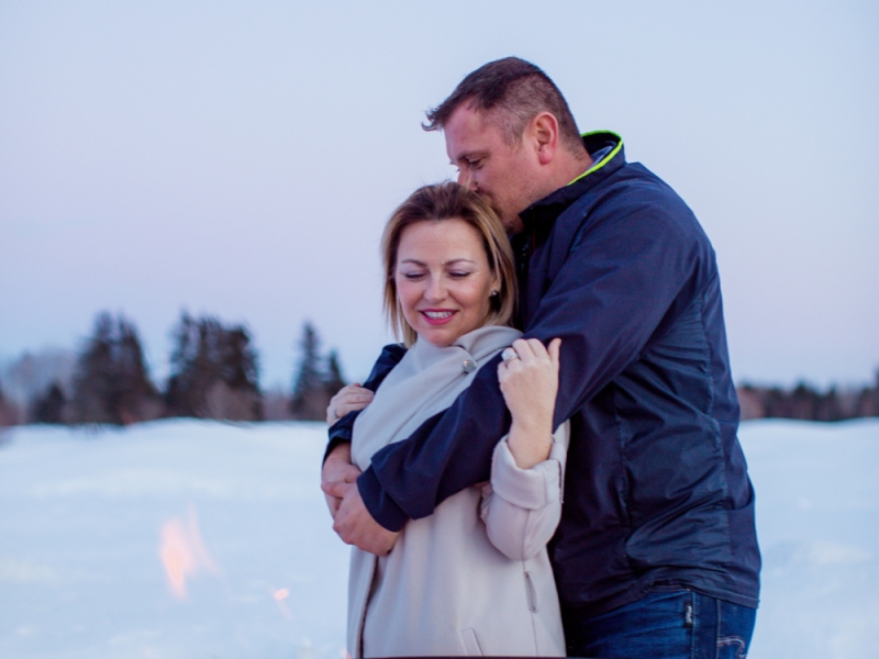 Couple embrace near outdoor fire pit in winter