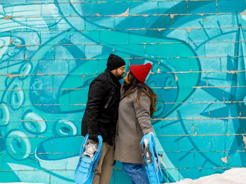 Couple gets close in front of wall mural in winter