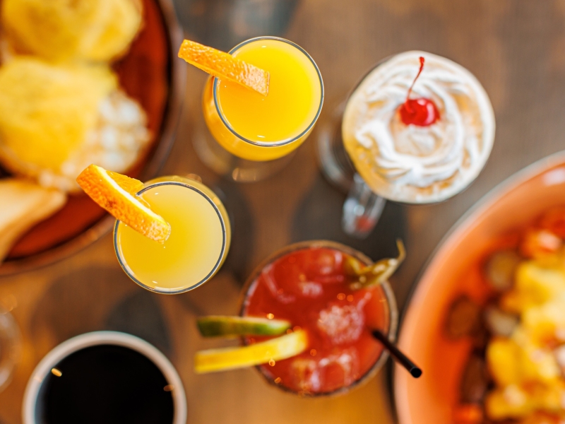 Overhead shot of mimosas, caesear and Irish coffee with plated brunch items