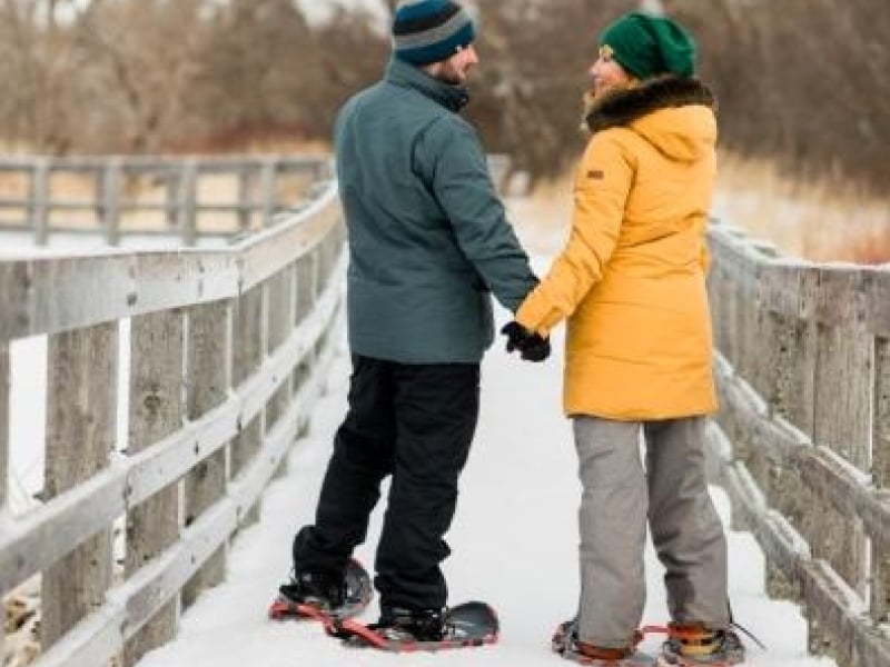 Couple holding hands on boardwalk while snowshoeing