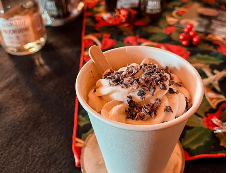 Close-up of cup of hot chocolate with bottles of liquors in background