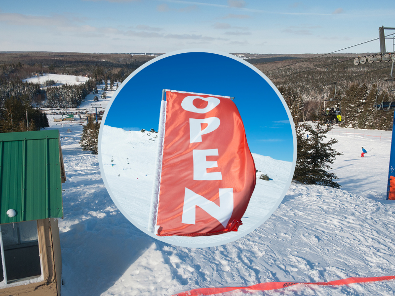 Red flag with OPEN in front and image of Brookvale Ski Park looking down hill in background