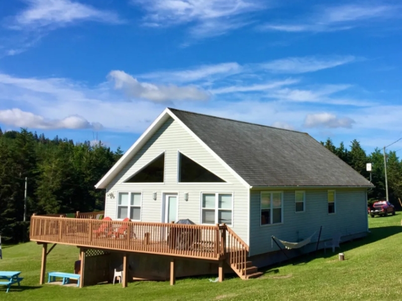 Outside view of beige cottage with large front deck