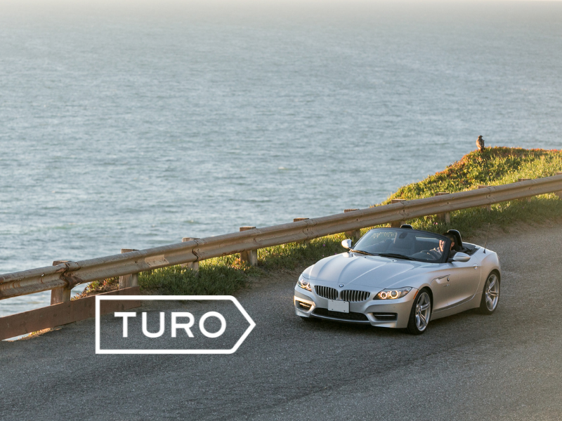 Stock image of car driving along coastline with TURO logo