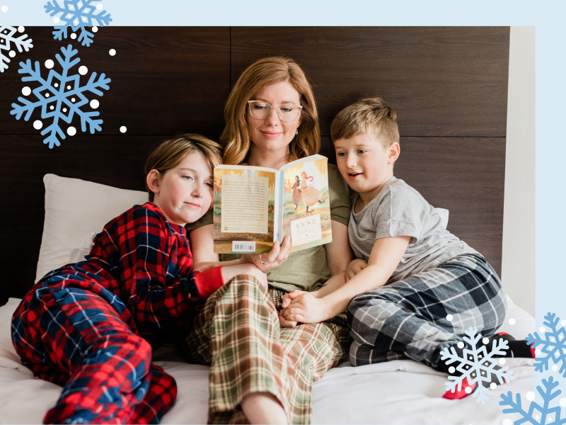 Adult with two children reading a book in hotel room, PEI