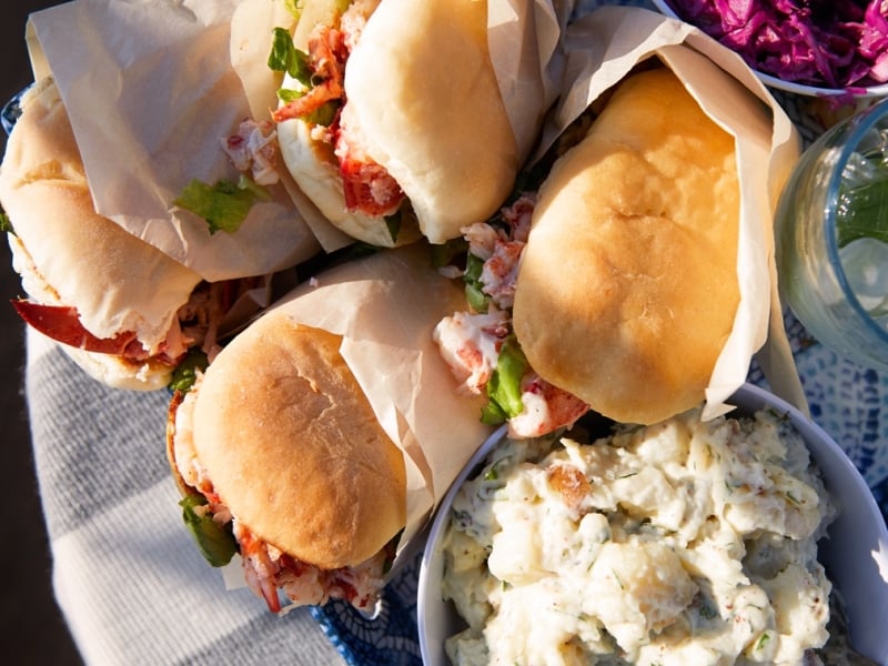 A picnic of lobster rolls, potato salad and purple coleslaw