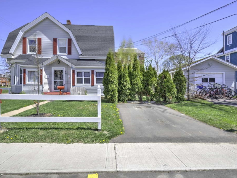 Photo of front of a grey house with red shutters