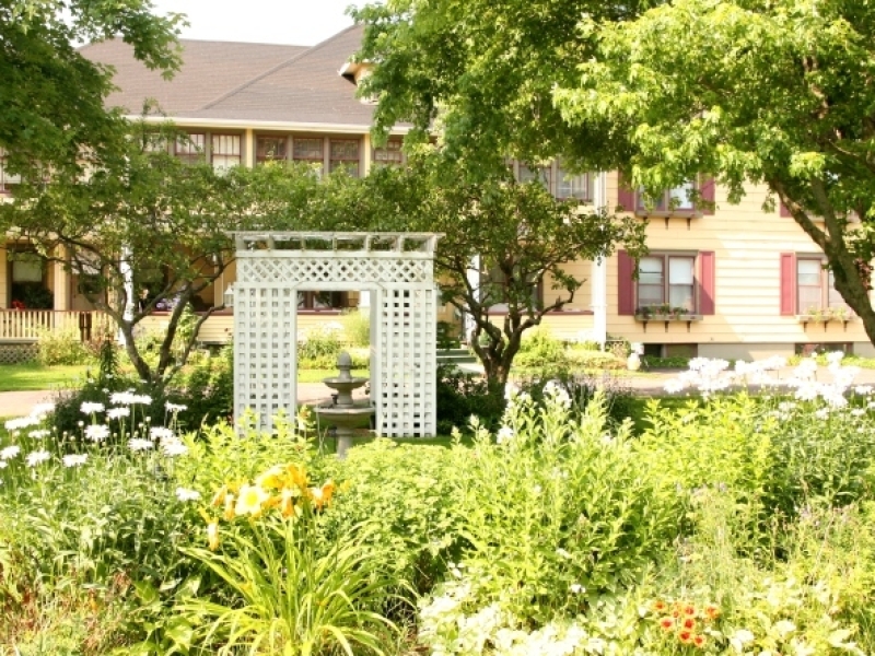 Exterior view of garden in full bloom in front and Chez Shea in background