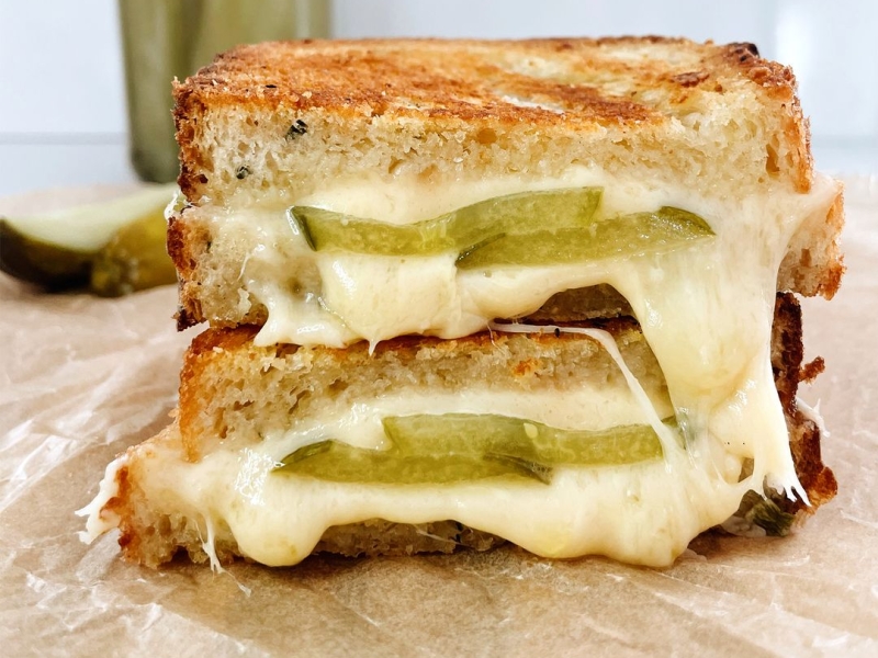 Dill Pickle and Smoked Cheddar Grilled Cheese sandwich cut in half