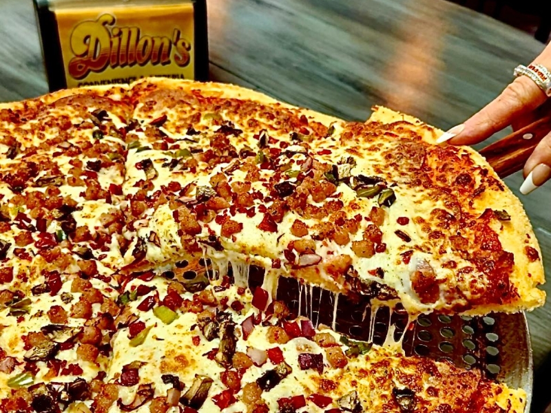 Large pizza sitting on table with Dillon's logo on napkin holder in background