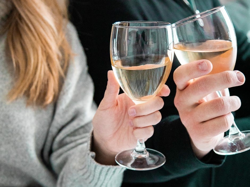 photo of two peoples hands holding wine