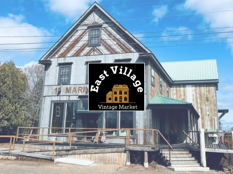 East Village Vintage Market logo in front with Mariners Lane building in background
