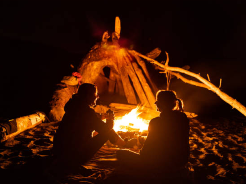 Two people enjoy fire on beach