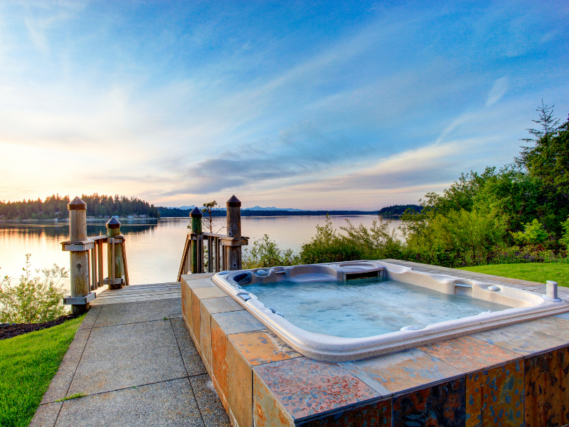 Stock image of outdoor hot tub near steps to water at a cottage