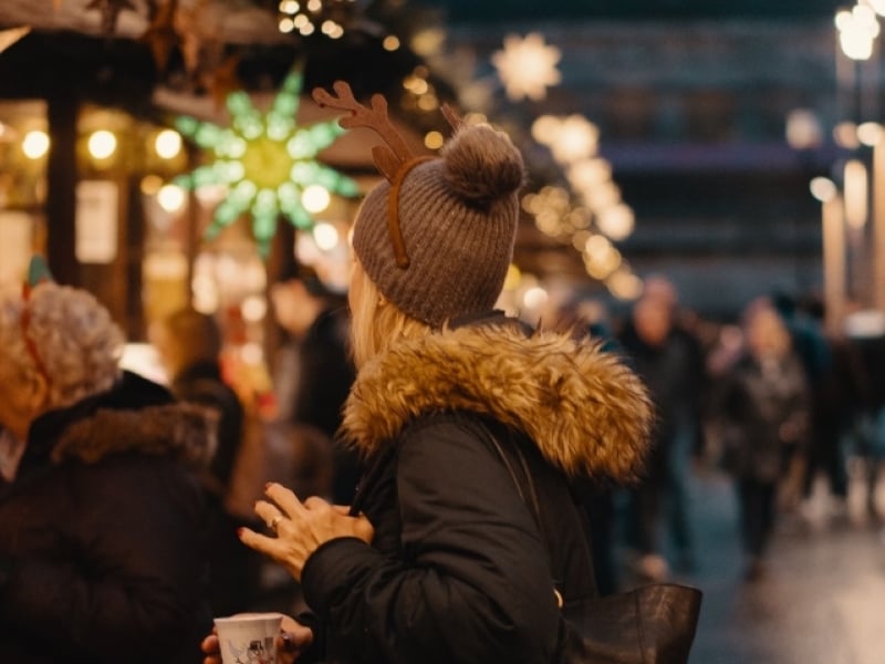 Woman in winter gear under lights of market