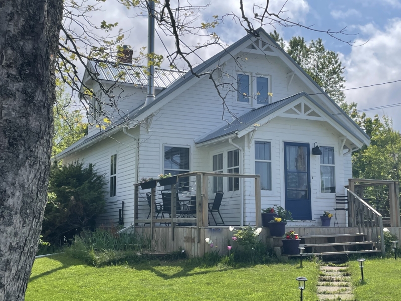 outside photo of exterior of the rise and shine guest house. white house with porch and deck on front