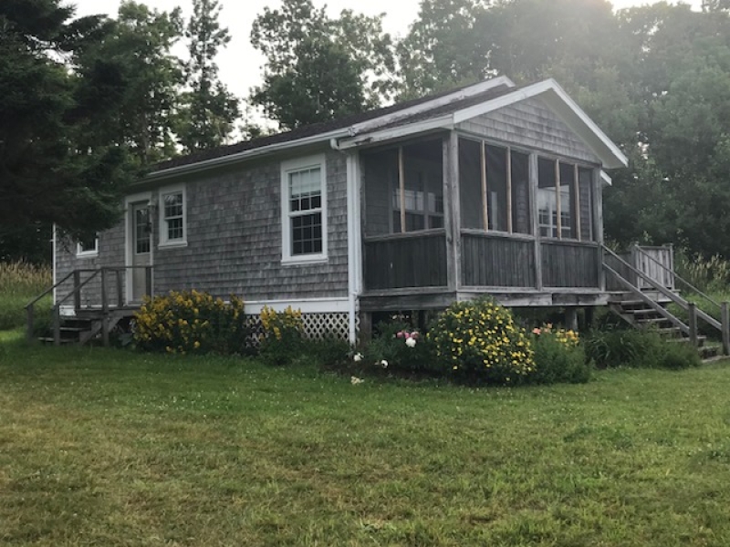 photo looking at front of Rosepath cottage. grey cottage with screened porch