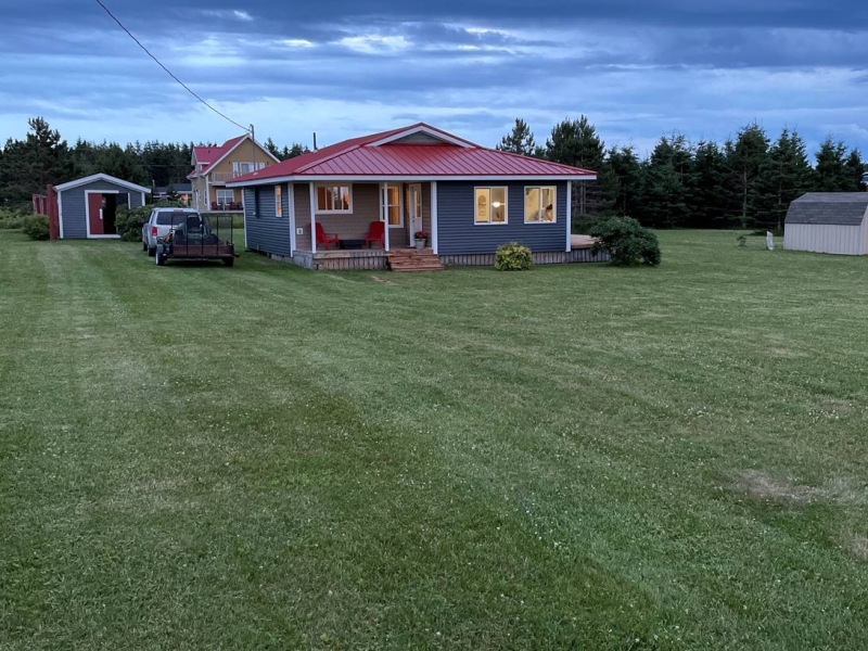 outside evening view of a blue cottage with a red roof