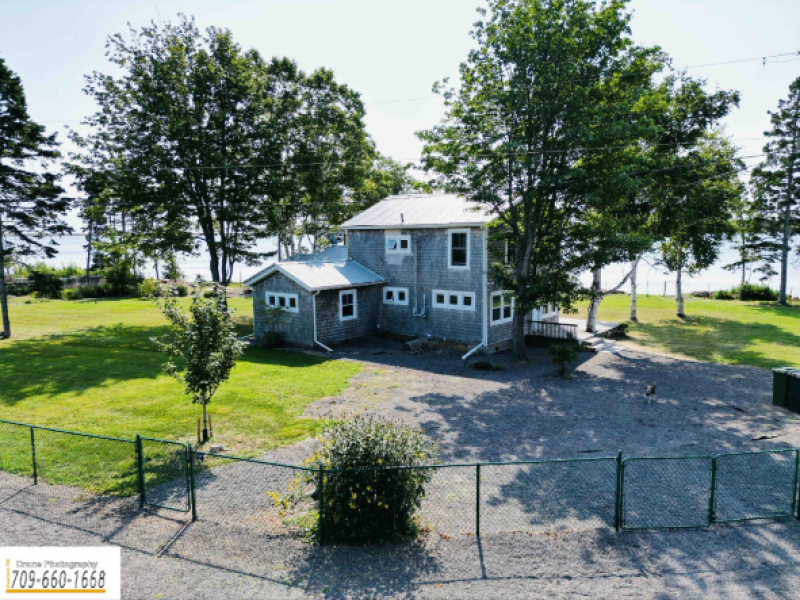 outside view of a large grey cottage overlooking the water 