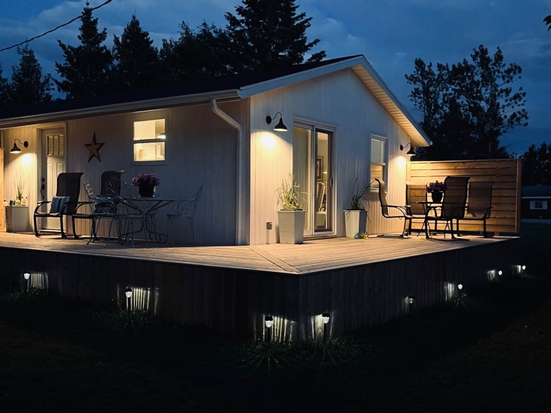 Nighttime photo of exterior white cottage with deck