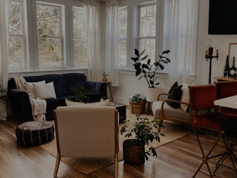picture of the living room at The Peter's homestead. dark couch and two beige chairs in a circle around a coffee table on a rug
