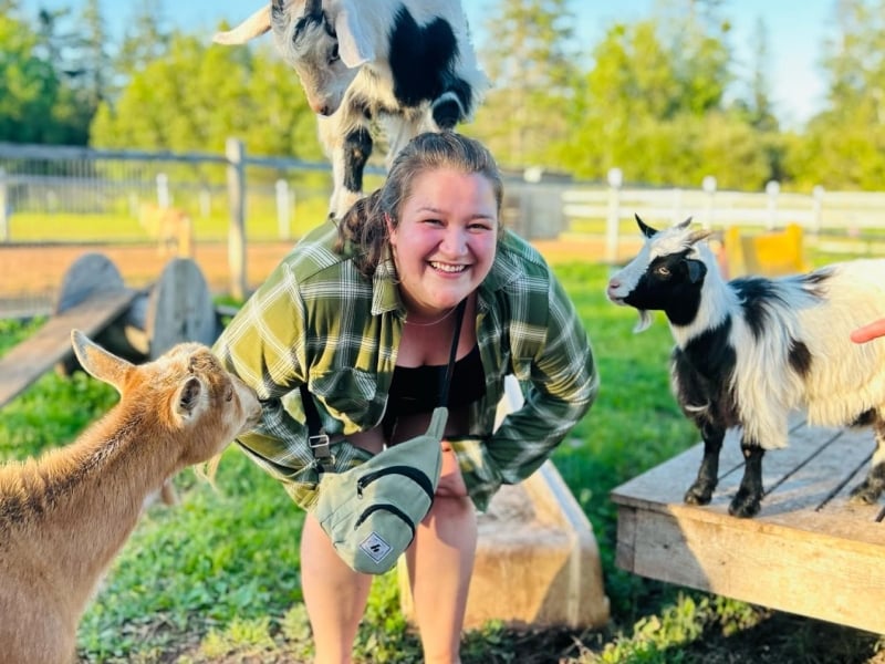 Young woman playing with goats at Whispering Hope Farm