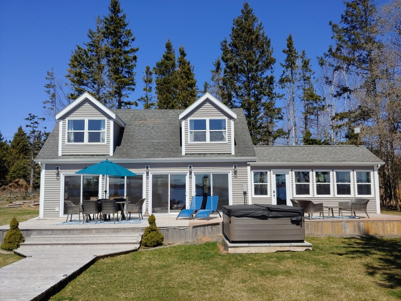 large grey cottage with many windows and large deck