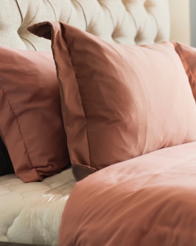 Close up of tufted headboard, pillows and blanket on bed