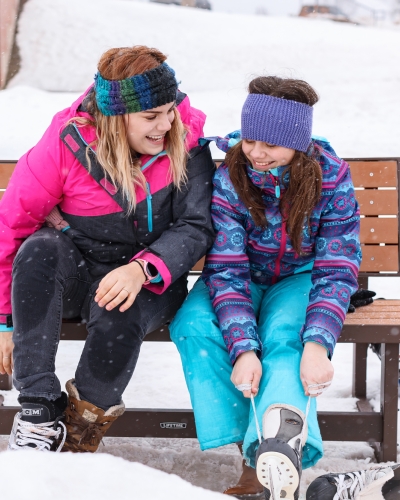 Adult and child females sitting on bench putting on skates