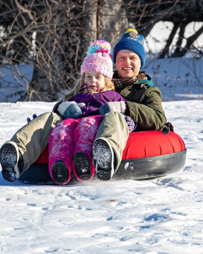 Adult male and child on tube on sledding hill, PEI