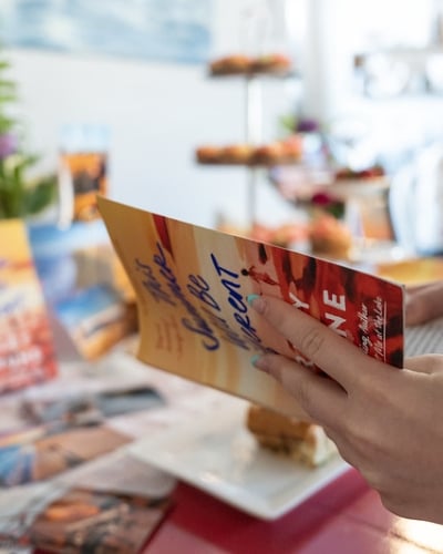 Person holds open copy of "This Summer Will Be Different" book at event