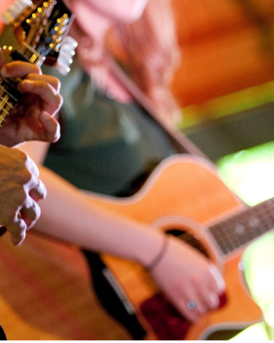 CLose-up of two people holding guitars and performing on stage 