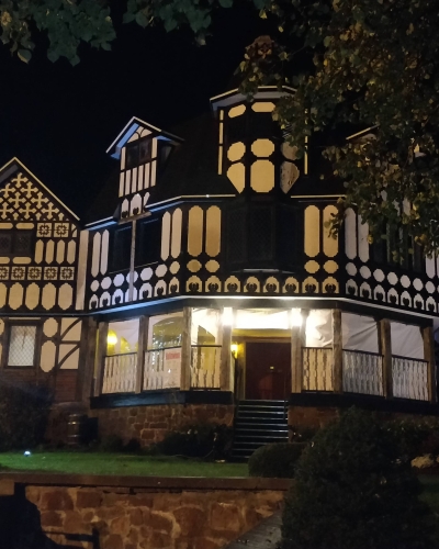 Exterior view of the Haunted Mansion at night with spooky lights