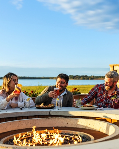 Group sit around a propane fire pit on the patio at Lone Oak Brew Pub