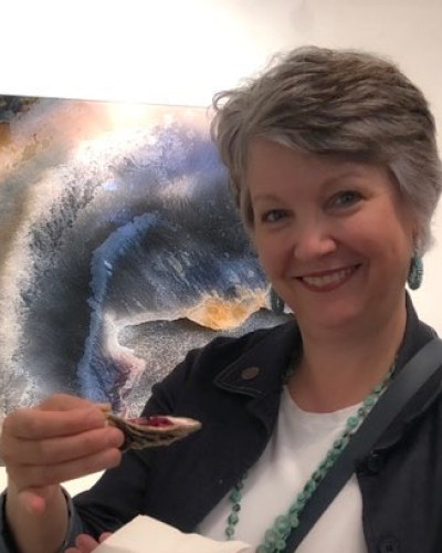 Image of Verna Lynne Weeks holding an oyster and standing in front of Oyster Art