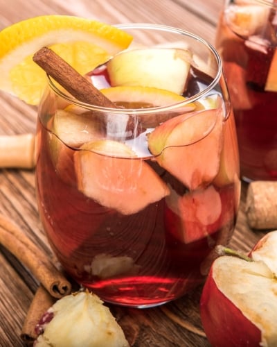 Stock image of two glasses of apple sangria with cork screw and halved apple to the side