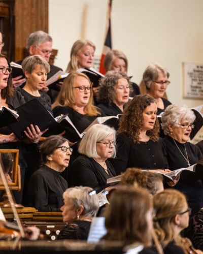 photo of a large group of choir singers holding books and singing